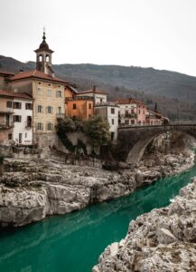 Scenic view of an Italian village with colorful houses by a vibrant emerald river.